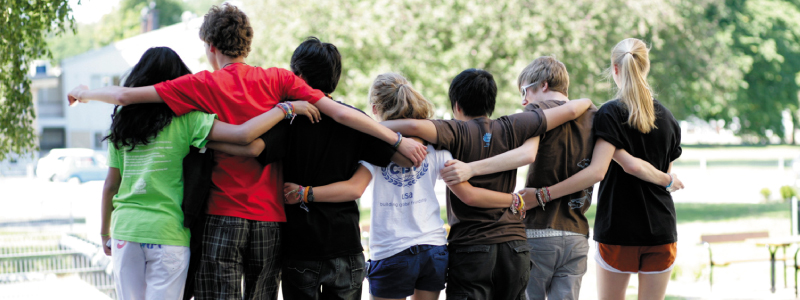 Eine Gruppe von Teilnehmer*innen eines CISV Programms stehen Arm in Arm