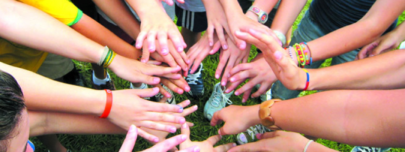 Die Teilnehmer*innen eines CISV Programms stecken ihre Hände in einem Kreis zusammen